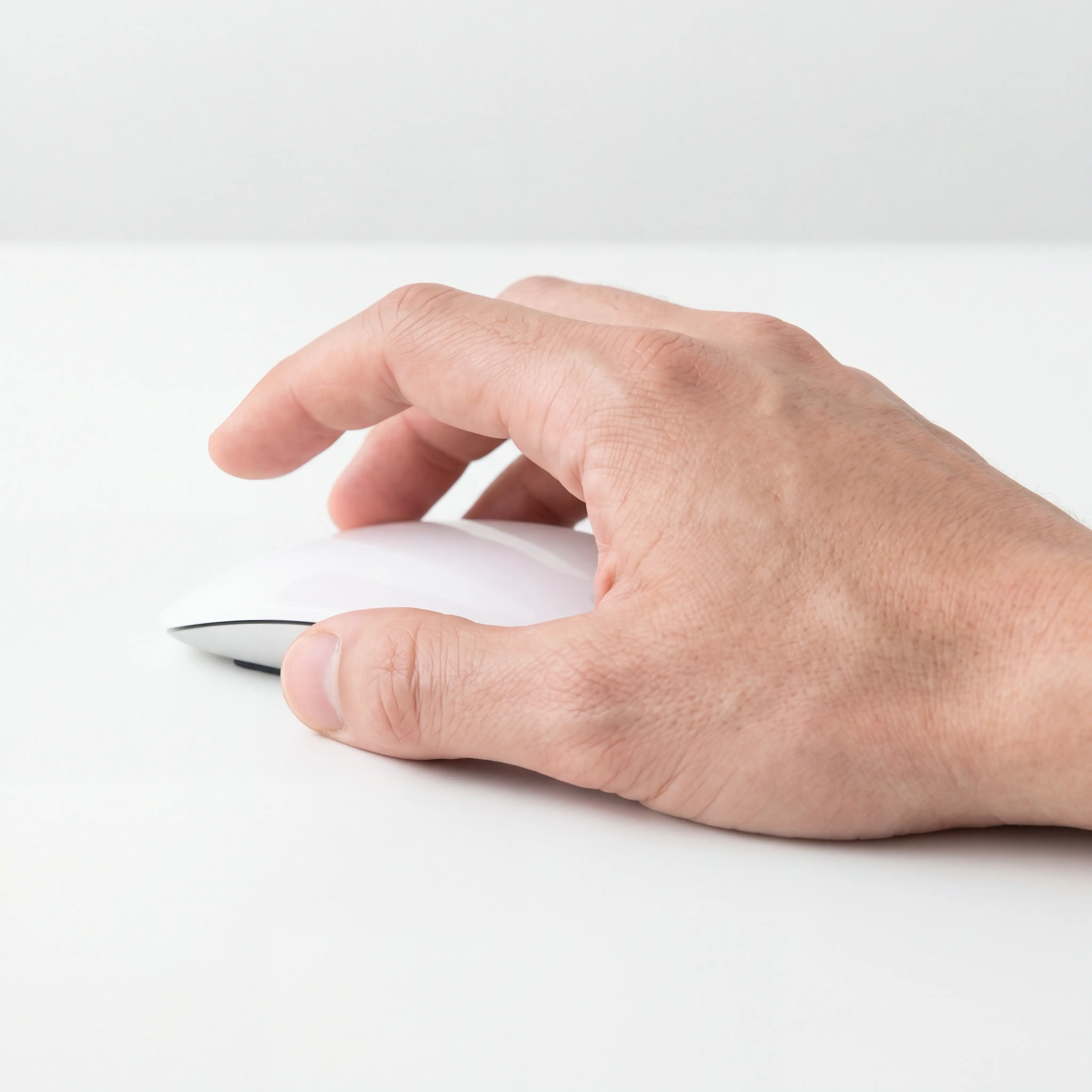 A thin mouse and the hand holding it. The index finger is raised, and the left mouse button is not pressed.